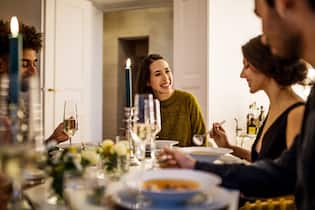 Superfoods für einen gesunden Herbst Smiling young woman talking with friends while having dinner at home