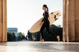 Surf in the City Young woman with surfboard on the way to Eisbach, Munich, Germany