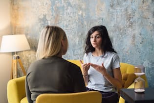 So kommt man am schnellsten zu psychologischer Hilfe Woman psychologist talking to patient woman. Therapist's gestures. Female talking in coworking office