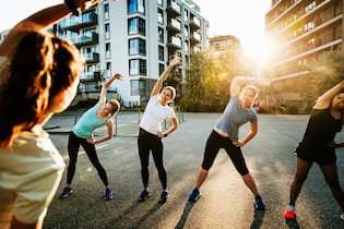 Workout-Trend Social Fitness macht auch die Psyche fit An urban fitness group for women warming up before a run through the city together.