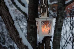 Entdeckt mit uns aussergewöhnliche Lichter- und Engelwege White old lantern hanging from a tree branch. Photographed during Christmastime in Finland. You can see some snow and trees in addition to the lantern in this photo. Semicloseup.