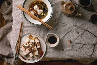 Vegis aufgepasst: So kommt ihr zu euren Proteinen Japanese Miso broth soup with silk tofu cubes. soy beans edamame. green beans in traditional bowl with chopsticks. ceramic teapot and cups on grey linen table cloth. Asian dinner. Flat lay. space. (Photo by: Natasha Breen/REDA&CO/Universal Images Group via Getty Images)