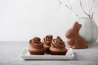Was machen mit all den übrigen Schoggihasen? Happy Easter greeting with delicious chocolate caramel cupcakes and bunny on gray background