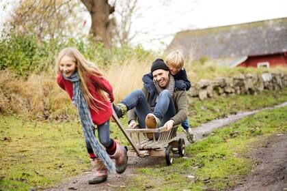 4 schwedische Traditionen für einen entspannten Familienalltag Children (8-12) pushing and pulling father in go cart on country lane