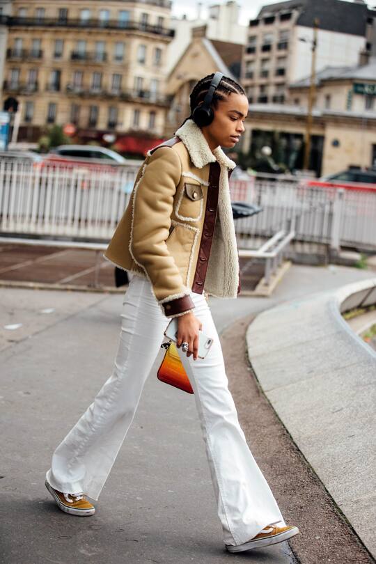 PARIS, FRANCE - MARCH 04: Model Alexis Sundman wears black headphones, a tan Coach shearling jacket, white flare jeans, and yellow Vans sneakers after the Giambattista Valli show during Paris Fashion Week Fall/Winter 2019 on March 04, 2019 in Paris, France. (Photo by Melodie Jeng/Getty Images)