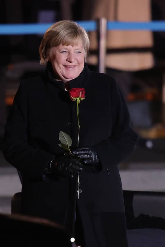 BERLIN, GERMANY - DECEMBER 02: (Editors note: Recrop of image #1356826168) Outgoing German Chancellor Angela Merkel holds a red rose at the conclusion of her military tattoo ceremony hosted by the Bundeswehr on December 02, 2021 in Berlin, Germany. Merkel will be stepping down soon to make way for German Social Democrat (SPD) Olaf Scholz, who will lead a coalition government of SPD, Greens and German Free Democrats (FDP). (Photo by Sean Gallup/Getty Images)