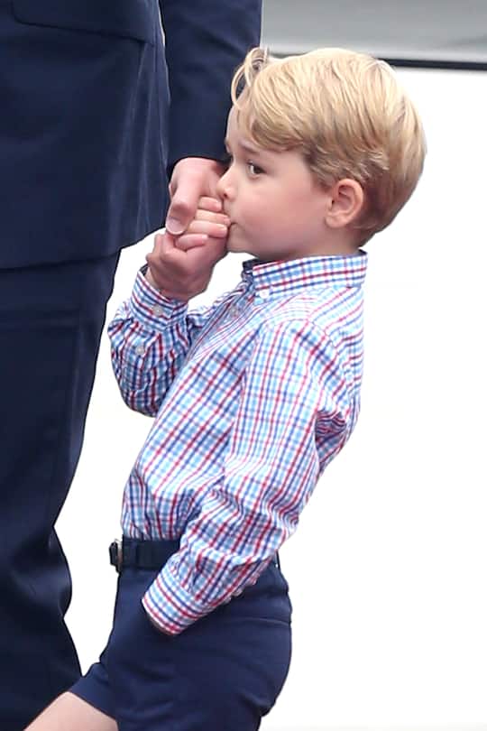 WARSAW, POLAND - JULY 17: Prince George of Cambridge kisses his father, Prince William, Duke of Cambridge hand as they arrive at Warsaw Airport during an official visit to Poland and Germany on July 17, 2017 in Warsaw, Poland. (Photo by DMC/GC Images)