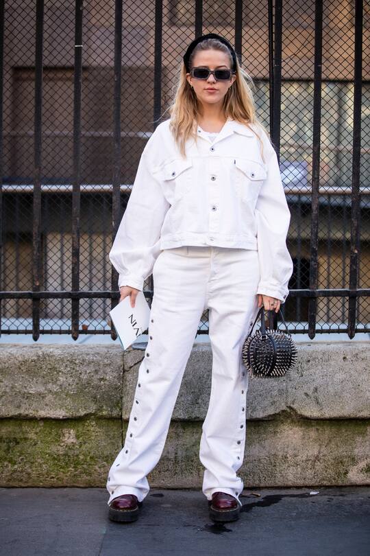 PARIS, FRANCE - FEBRUARY 27: A guest, wearing a white denim jacket with matching jeans, burgundy Dr. Martens, black studded bag and black hairband, is seen outside Lanvin on Day 3 Paris Fashion Week Autumn/Winter 2019/20 on February 27, 2019 in Paris, France. (Photo by Claudio Lavenia/Getty Images)