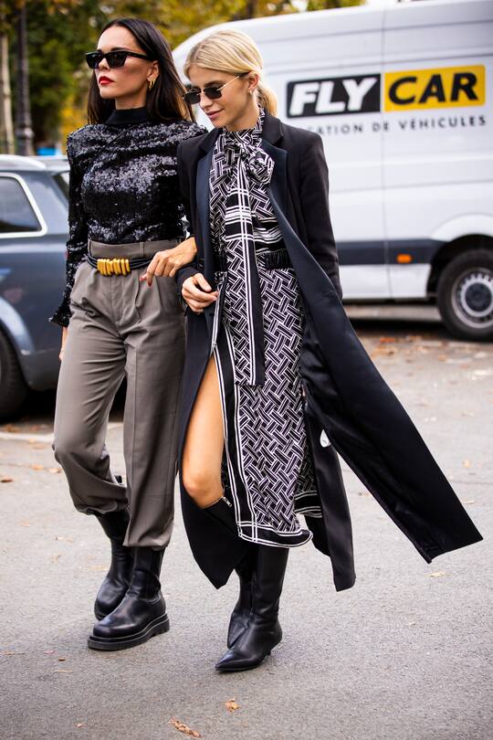 PARIS, FRANCE - SEPTEMBER 28: Evangelie Smyrniotaki (L), wearing a black sequins top, grey pants and gold belt, and Caro Daur (R), wearing a black and white printed dress and long black coat, are seen outside the Elie Saab show during Paris Fashion Week - Womenswear Spring Summer 2020 on September 28, 2019 in Paris, France. (Photo by Claudio Lavenia/Getty Images)