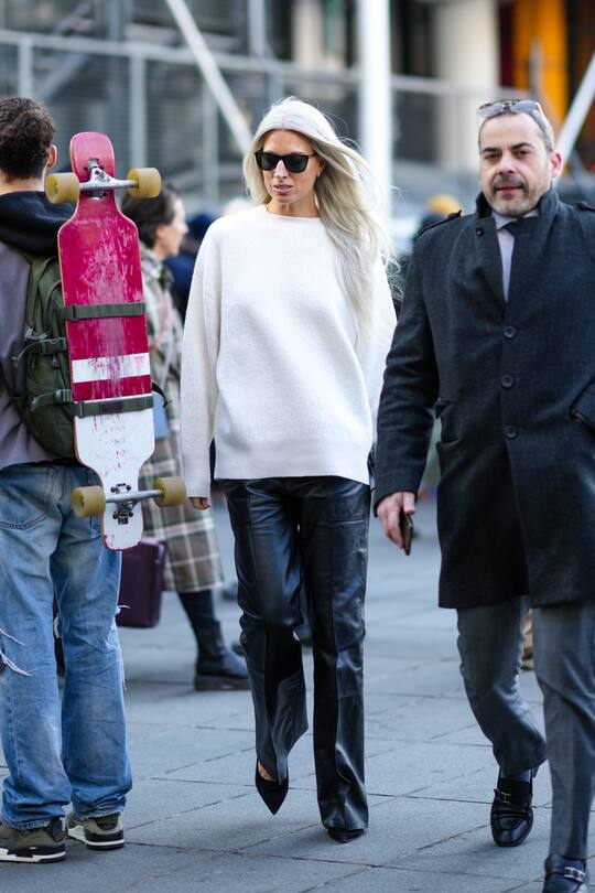 PARIS, FRANCE - MARCH 07: Sarah Harris wears black sunglasses, a white wool pullover, black shiny leather large pants, black suede pointed pumps heels shoes, outside Stella McCartney, during Paris Fashion Week - Womenswear F/W 2022-2023, on March 07, 2022 in Paris, France. (Photo by Edward Berthelot/Getty Images)