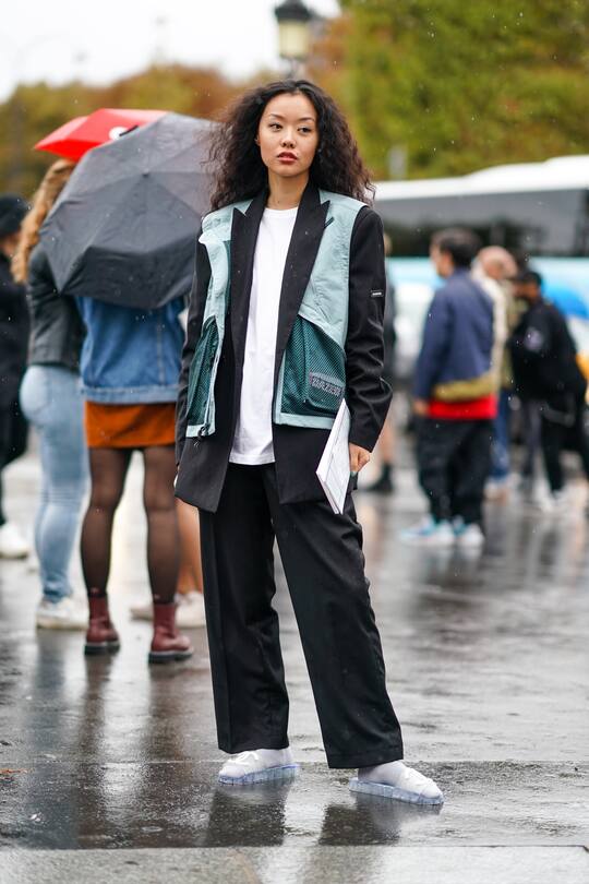 PARIS, FRANCE - OCTOBER 01: A guest wears a white top, a black Balenciaga jacket, a green sleeveless vest, black wide-legs pants, Chanel vinyl slides sandals, outside Chanel, during Paris Fashion Week - Womenswear Spring Summer 2020, on October 01, 2019 in Paris, France. (Photo by Edward Berthelot/Getty Images)