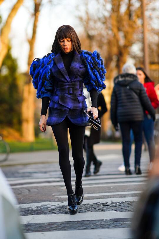 PARIS, FRANCE - JANUARY 21: A guest wears a black top, a purple and black checkered jacket decorated with blue and black wool braids, a matched mini skirt, black opaque tights, shiny T-trap black platform heeled pumps, a tiny black Jacquemus bag, outside Alexandre Vauthier, during Paris Fashion Week - Haute Couture Spring/Summer 2020, on January 21, 2020 in Paris, France. (Photo by Edward Berthelot/Getty Images )