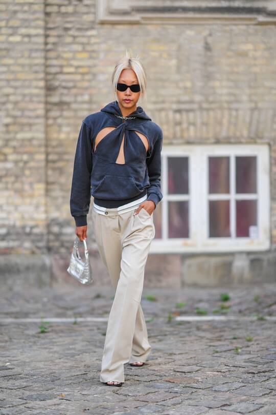 COPENHAGEN, DENMARK - AUGUST 09: Vanessa Hong wears black cat eyes sunglasses, a silver large chain necklace, a dark gray cut-out pattern sweater, beige wide legs suit pants, a silver shiny varnished leather handbag, pumps heels shoes, outside Aeron, during Copenhagen Fashion Week Spring/Summer 2023, on August 09, 2022 in Copenhagen, Denmark. (Photo by Edward Berthelot/Getty Images)