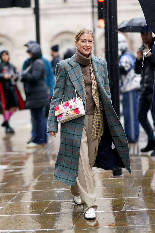 LONDON, ENGLAND - FEBRUARY 16: Emili Sindlev wears a green checked long coat, a floral print Chanel bag, a brown wool turtleneck pullover, beige flowing pants, white shoes, during London Fashion Week Fall Winter 2020 on February 16, 2020 in London, England. (Photo by Edward Berthelot/Getty Images)