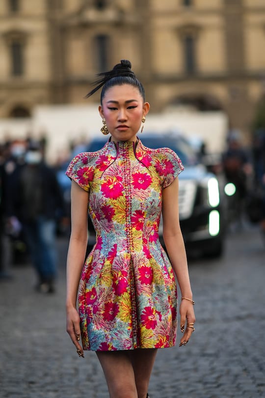 PARIS, FRANCE - OCTOBER 05: Jaime Xie wears gold large pendant earrings, a white / yellow / pink fuchsia flower print pattern laces high neck / short sleeves, outside Louis Vuitton, during Paris Fashion Week - Womenswear Spring Summer 2022, on October 05, 2021 in Paris, France. (Photo by Edward Berthelot/Getty Images)
