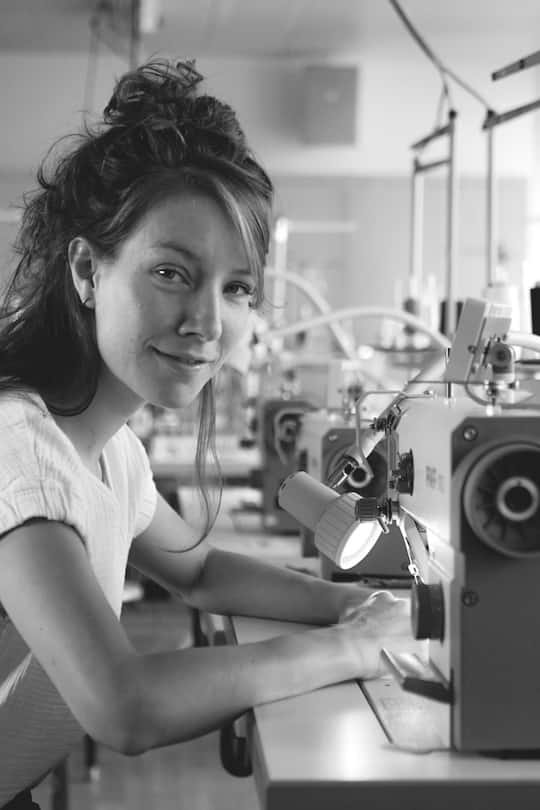 a young woman sitting at a sewing maschine