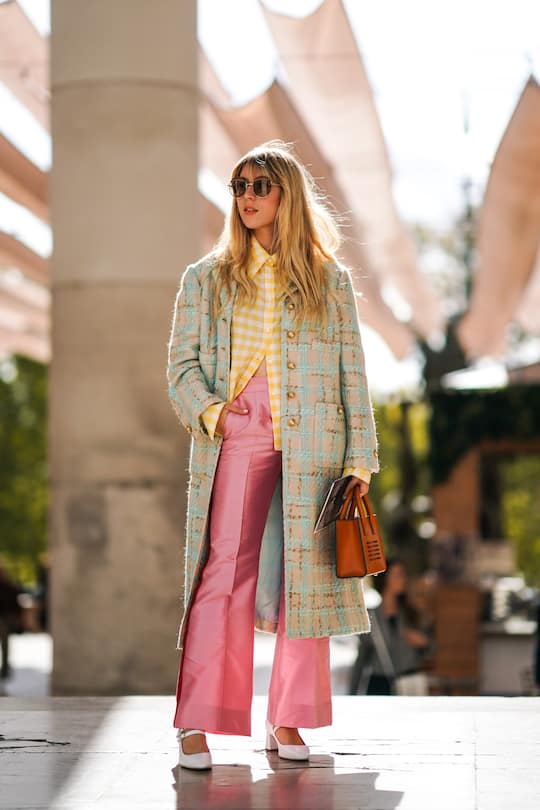 PARIS, FRANCE - SEPTEMBER 30: Emma Bonneaud wears sunglasses, a yellow and white checkered shirt, a beige and light turquoise blue tweed coat with brass buttons, lustrous pink flare pants, a tan-color handbag with the inscription " Believe in extraordinary ", white shoes, during Paris Fashion Week - Womenswear Spring Summer 2020, on September 30, 2019 in Paris, France. (Photo by Edward Berthelot/Getty Images)