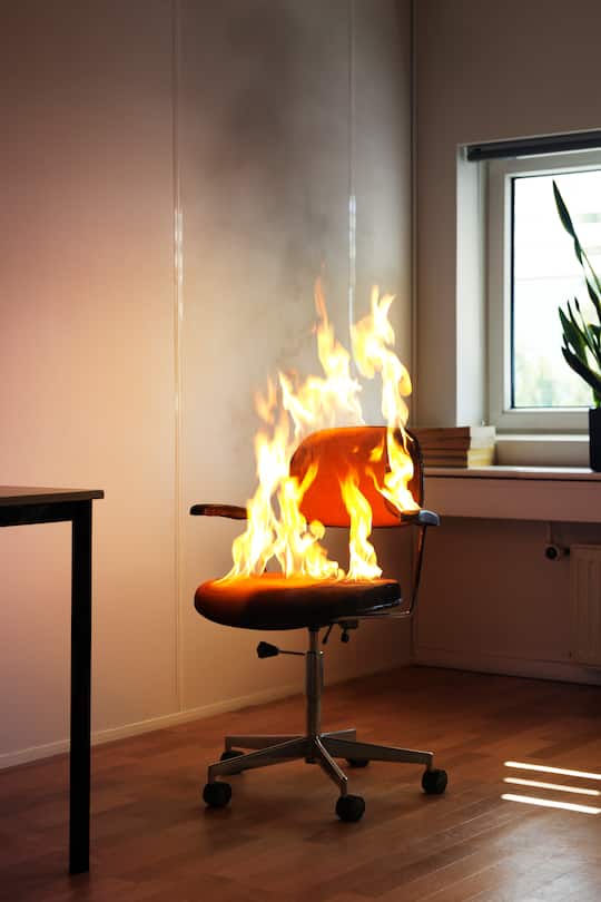 Office interior with chair engulfed in fire flames