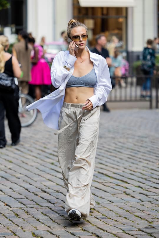COPENHAGEN, DENMARK - AUGUST 09: A guest is seen wearing cropped grey top, button shirt, beige pants outside A. Roege Hove during Copenhagen Fashion Week Spring/Summer 2023 on August 09, 2022 in Copenhagen, Denmark. (Photo by Christian Vierig/Getty Images)