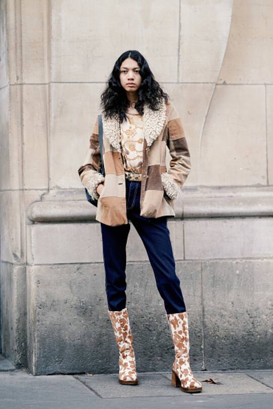 PARIS, FRANCE - JANUARY 16: A model wears a brown jacket with white wool inner lining, blue pants, boots with brown cow print, outside Acne Studios, during Paris Fashion Week Menswear F/W 2019-2020, on January 16, 2019 in Paris, France. (Photo by Edward Berthelot/Getty Images)