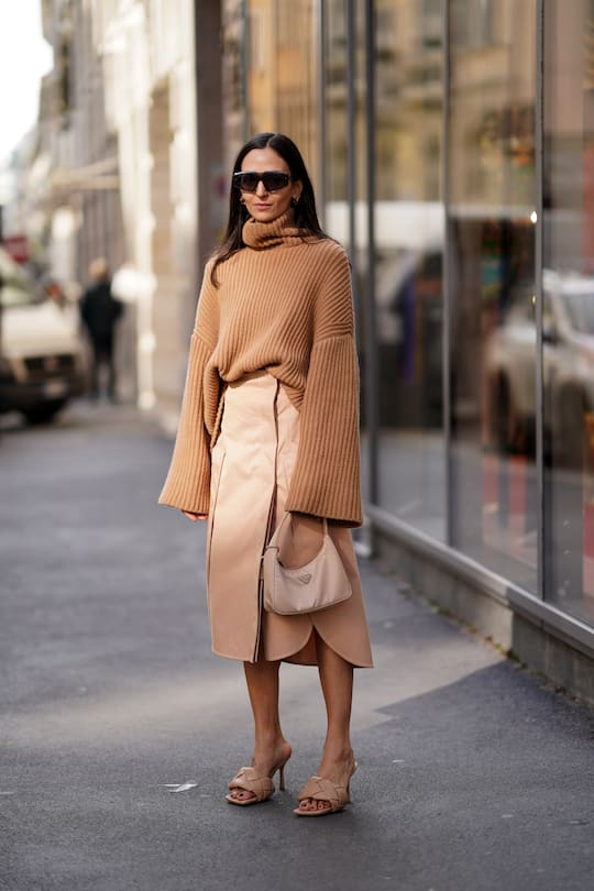 MILAN, ITALY - FEBRUARY 21: A guest wears sunglasses, a brown turtleneck oversized wool pullover with flared sleeves, a skirt, a Prada bag, salmon-colored padded leather sandals, outside Sportmax, during Milan Fashion Week Fall/Winter 2020-2021 on February 21, 2020 in Milan, Italy. (Photo by Edward Berthelot/Getty Images)