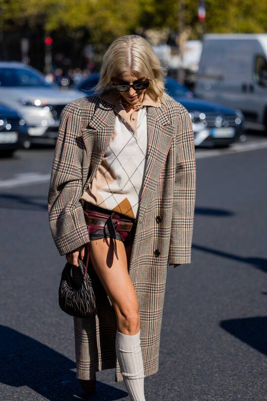 PARIS, FRANCE - OCTOBER 04: Caroline Caro Daur wears oversized checkered coat, shorts, pull under, socks, black bag outside Miu Miu during Paris Fashion Week - Womenswear Spring/Summer 2023 : Day Nine on October 04, 2022 in Paris, France. (Photo by Christian Vierig/Getty Images)