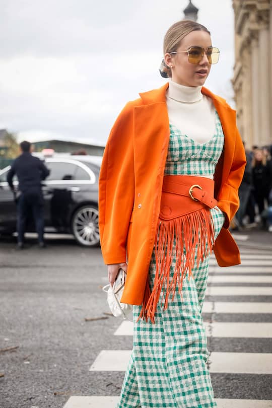PARIS, FRANCE - FEBRUARY 27: A guest wearing orange jacket, green and white check jumpsuit, orange leather belt, vintage sunglasses and white Bottega Veneta mini bag outside the Paco Rabanne show during the Paris Fashion Week Womenswear Fall/Winter 2020/2021 on February 27, 2020 in Paris, France. (Photo by Hanna Lassen/Getty Images)