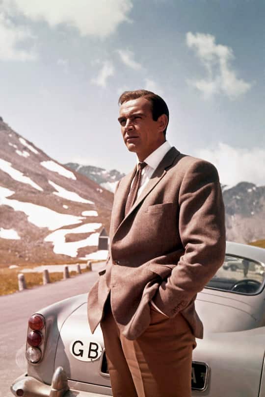 1964: Actor Sean Connery poses as James Bond next to his Aston Martin DB5 in a scene from the United Artists film 'Goldfinger' in 1964 (Photo by Donaldson Collection/Michael Ochs Archives/Getty Images)