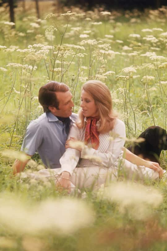 Her Royal Highness Princess Anne and Captain Mark Phillips pose for an engagement portrait in a meadow. (Photo by © Norman Parkinson Achive/Iconic Images/Getty Images)