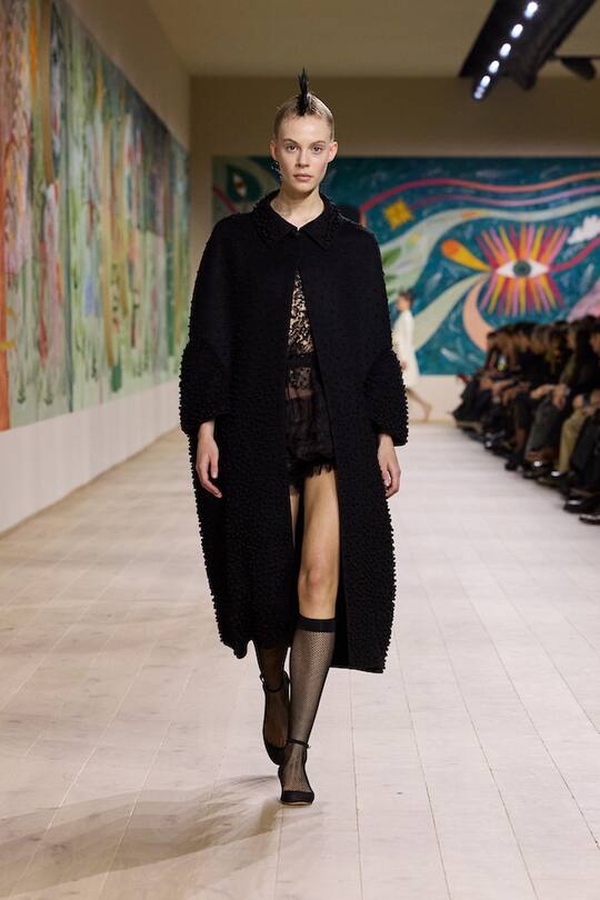 a model in black walking down the runway