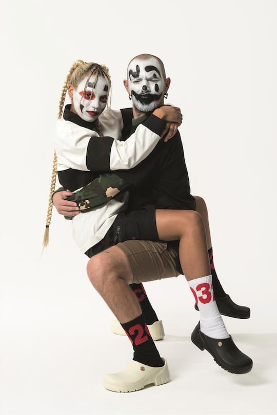 two models with black and white painted faces holding each other