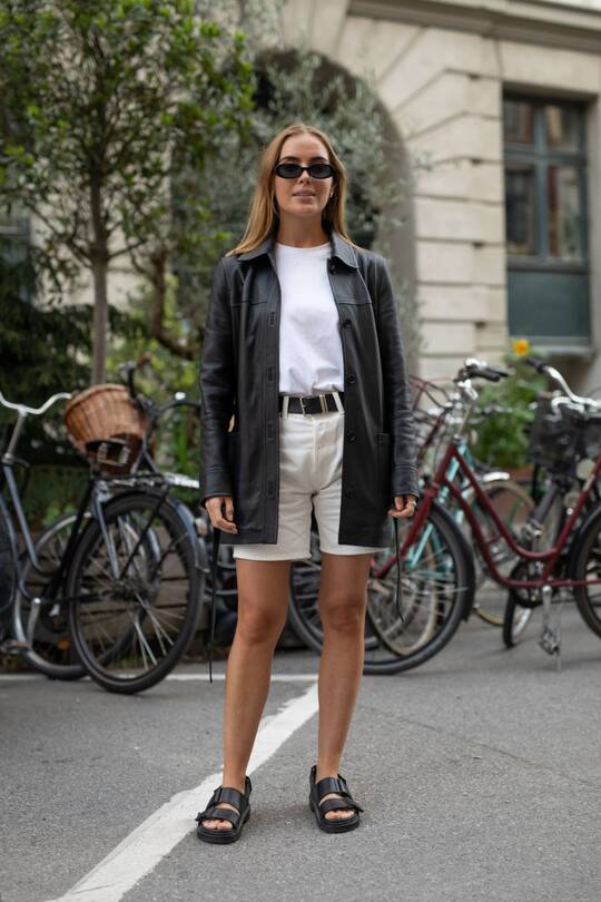 COPENHAGEN, DENMARK - AUGUST 07: A guest is seen on the street attending Copenhagen Fashion Week SS20 wearing black leather jacket, bone shorts, white tshirt, black sandals on August 07, 2019 in Copenhagen, Denmark. (Photo by Matthew Sperzel/Getty Images)