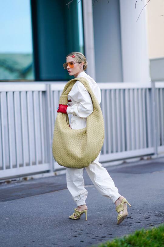 MILAN, ITALY - FEBRUARY 23: Sira Pevida wears orange glasses, a large oversized Bottega Veneta bag, a white jumpsuit, quilted shoes, outside BOSS, during Milan Fashion Week Fall/Winter 2020-2021 on February 23, 2020 in Milan, Italy. (Photo by Edward Berthelot/Getty Images)
