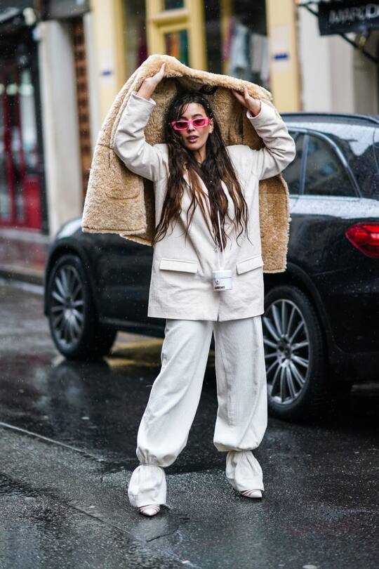 PARIS, FRANCE - MARCH 01: A guest wears a white oversized blazer jacket, white pants, pointy shoes, pink sunglasses, holds a brown fluffy coat, during Paris Fashion Week - Womenswear Fall/Winter 2020/2021, on March 01, 2020 in Paris, France. (Photo by Edward Berthelot/Getty Images)