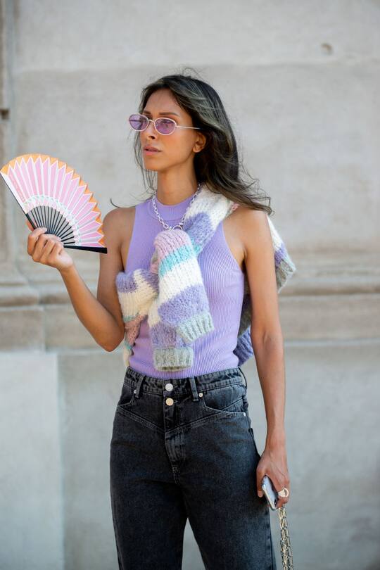 COPENHAGEN, DENMARK - AUGUST 11: Isabella Charlotta Poppius outside Remain Birger Christensen wearing jeans, purple top and sweater carrying paper folding fan during Copenhagen fashion week SS21 on August 11, 2020 in Copenhagen, Denmark. (Photo by Raimonda Kulikauskiene/Getty Images)