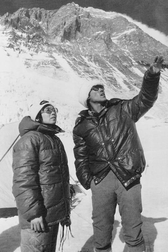 (Original Caption) Mt. Everest In Himalayas: Mrs. Junko Tabei (L), 35, the first woman ever to conquer the world's highest peak, stands against the background of the southern wall of Mt. Everest with Nepal's Sirdar Ang Tsering. Some two weeks after the picture was taken near the Second Camp, the two reached the summit of Mt. Everest 5/16.