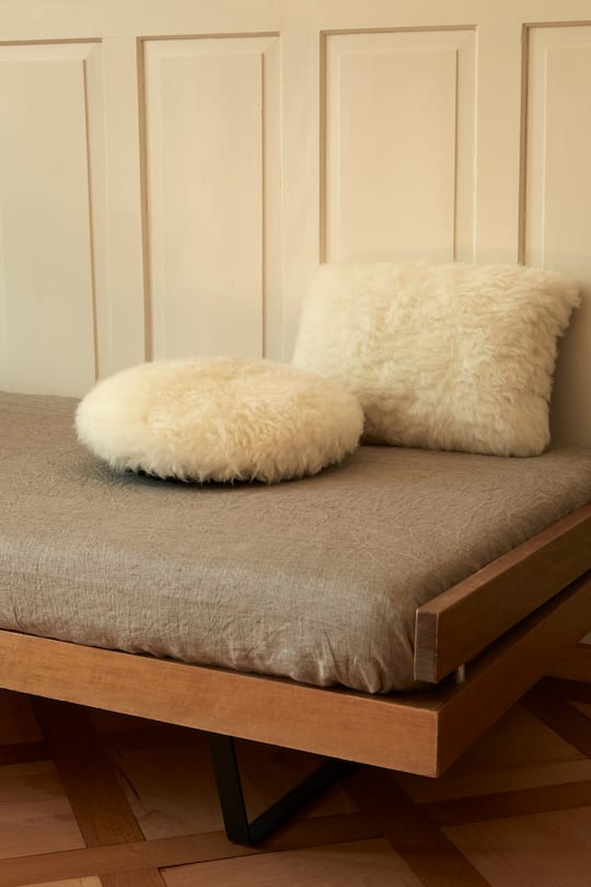 a grey couch with two white sheep wool cushions
