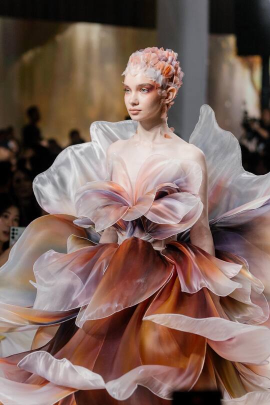 model walking down a catwalk wearing a flower dress