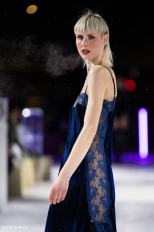 a blond model from the side wearing a dark blue night gown