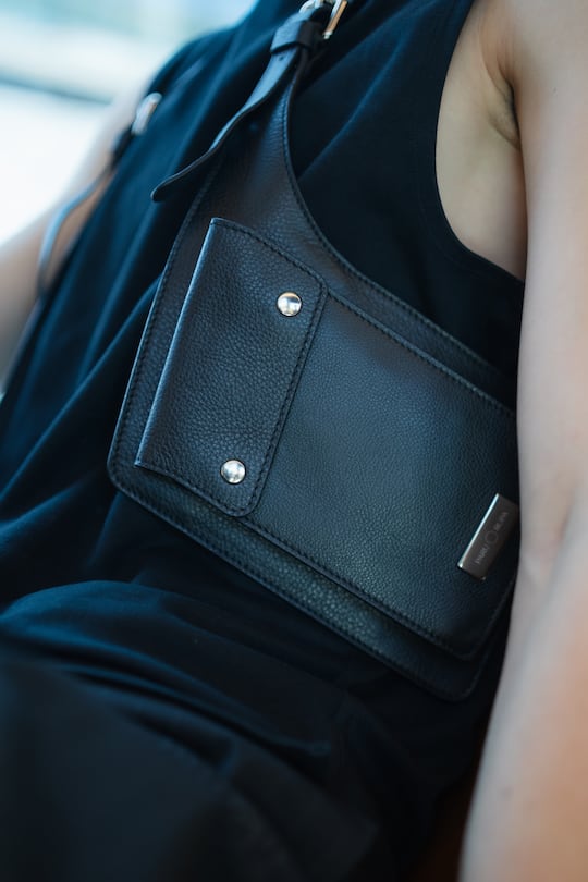 close up of a person holding a black leather bag