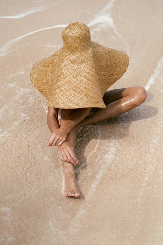 Frau am Strand mit riesigem Sonnenhut.