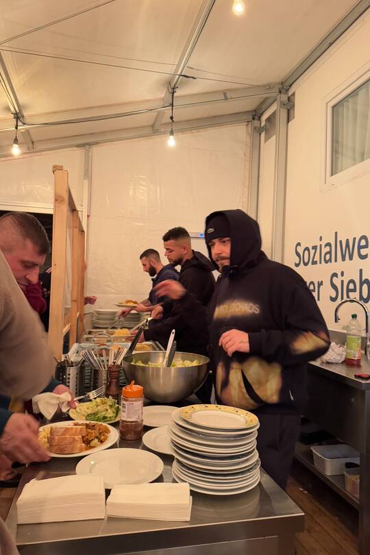 EAZ schöpft einem Bedürftigen im Pfuusbus sein Essen.