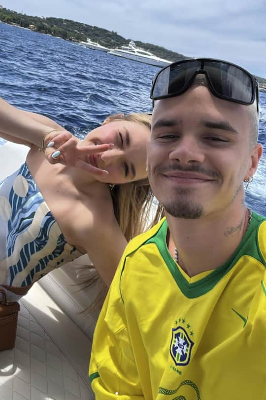 Auf einem Ferienfoto mit ihrem Bruder Romeo posiert Harper Beckham mit einer teuren Designer-Handtasche.