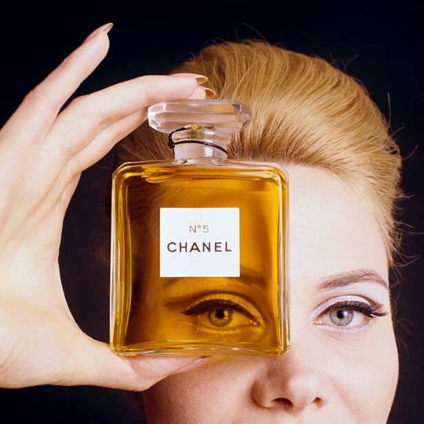 Close up of model holding a bottle of Chanel No. 5 perfume up to her eye as if looking through the bottle. (Photo by Fotiades/Condé Nast via Getty Images)