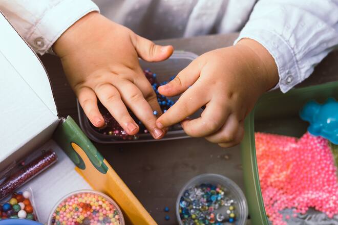 Kid hands doing art and crafts with slime, glitter and other stuff.