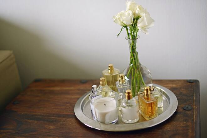 seven perfume bottles and a vase with roses on a perfume tray