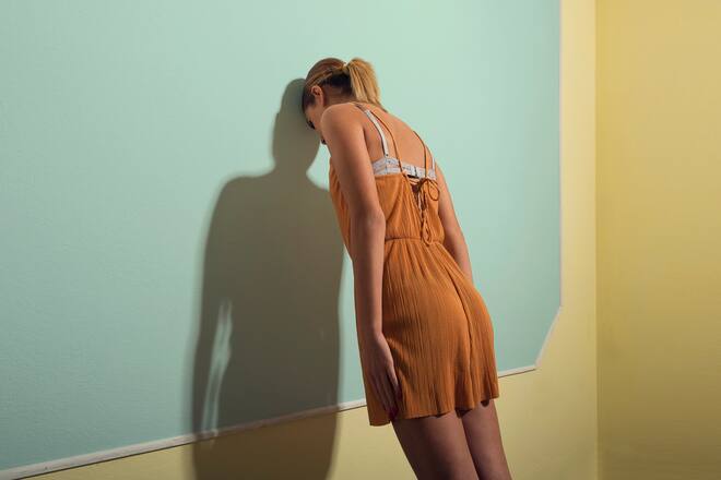 Frau, die mit dem Kopf and die Wand lehnt