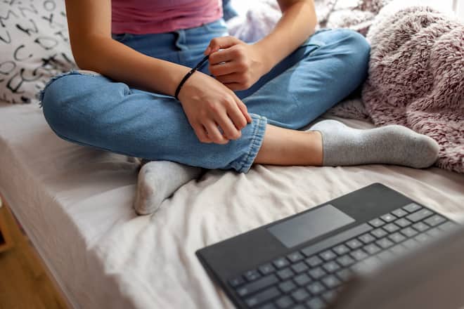 Cute 14 years old girl has psychotherapy session with her therapist via video call. She has rubber band on her wrist to prevent anxiety.