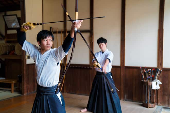 Two young adult Japanese Kyudo archers preparing to take their shots. Okayama, Japan. March 2017