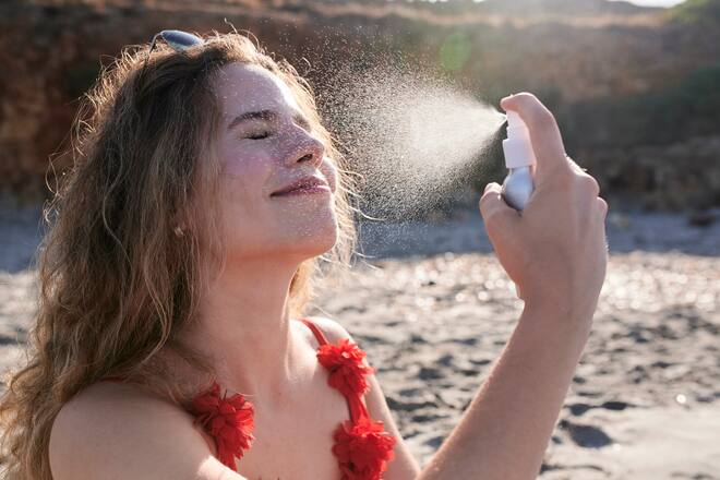 Frau mit Sprühflasche am Strand